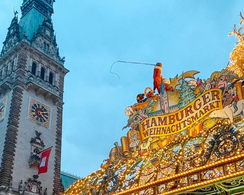 Beleuchteter Eingang zum Hamburger Weihnachtsmarkt auf dem Rathausmarkt. Im Hintergrund das Hamburger Rathaus.
